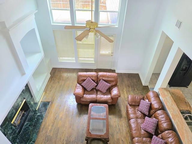 living area featuring visible vents, ceiling fan, wood finished floors, and a premium fireplace