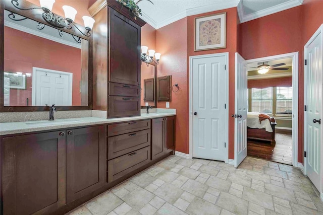 full bath featuring ensuite bathroom, a sink, baseboards, stone tile flooring, and ornamental molding