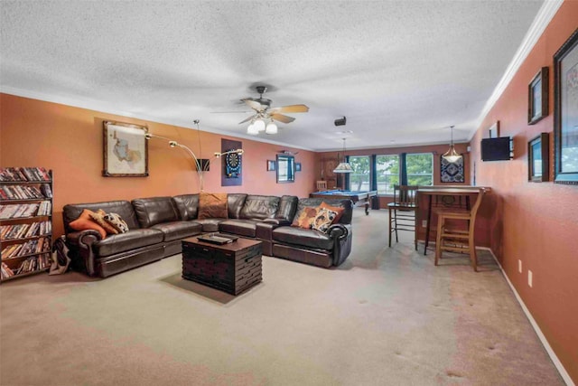 living room with a textured ceiling, carpet, a ceiling fan, baseboards, and ornamental molding