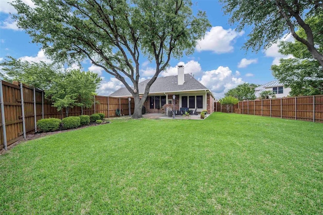 back of property with a patio, a fenced backyard, a chimney, a shingled roof, and a yard