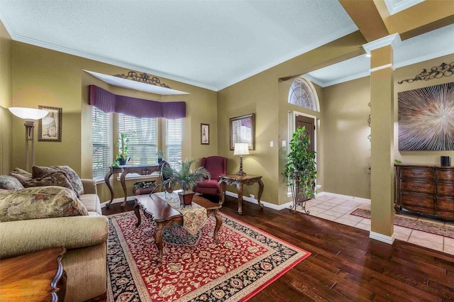 living area featuring a textured ceiling, baseboards, decorative columns, ornamental molding, and hardwood / wood-style flooring