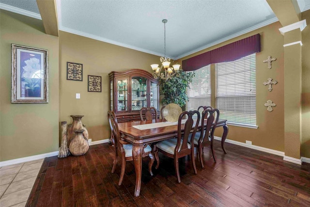 dining area featuring wood-type flooring, ornamental molding, a textured ceiling, and an inviting chandelier