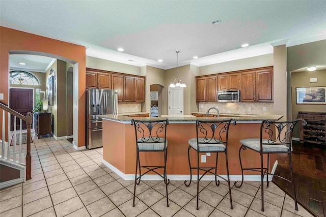 kitchen featuring arched walkways, appliances with stainless steel finishes, and a breakfast bar area