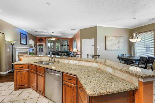 kitchen with stainless steel dishwasher, decorative light fixtures, brown cabinetry, and a sink