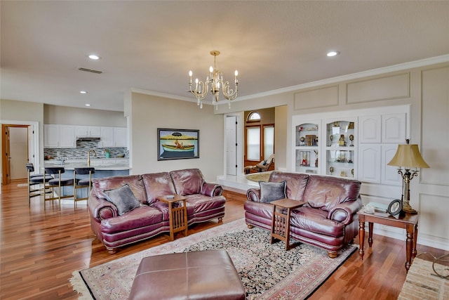 living room featuring an inviting chandelier, light wood-style floors, recessed lighting, and visible vents