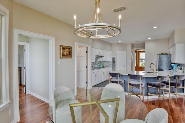 dining room with a notable chandelier, recessed lighting, baseboards, wood finished floors, and visible vents