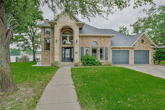 traditional home featuring a garage, a front lawn, fence, roof with shingles, and brick siding