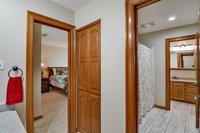 hallway featuring visible vents, a sink, and baseboards