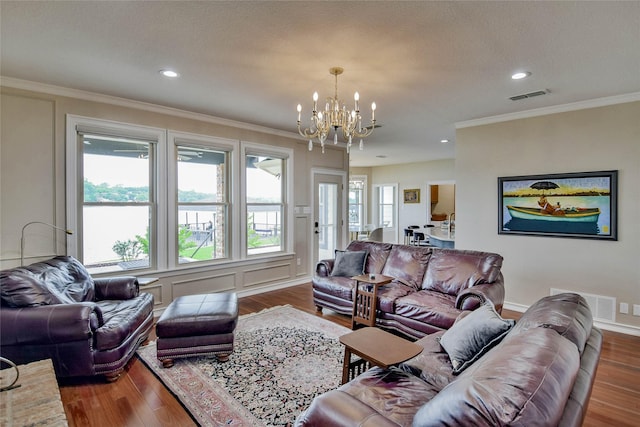 living room featuring visible vents, ornamental molding, wood finished floors, and a notable chandelier
