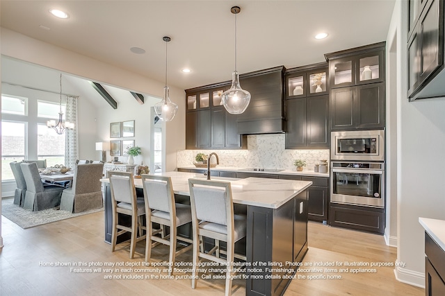 kitchen featuring backsplash, appliances with stainless steel finishes, a sink, light stone counters, and custom exhaust hood