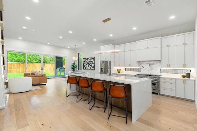 9409 Lenel Pl, Dallas, TX 75220 - kitchen featuring stainless steel appliances, tasteful backsplash, light wood-style floors, recessed lighting, and a spacious island