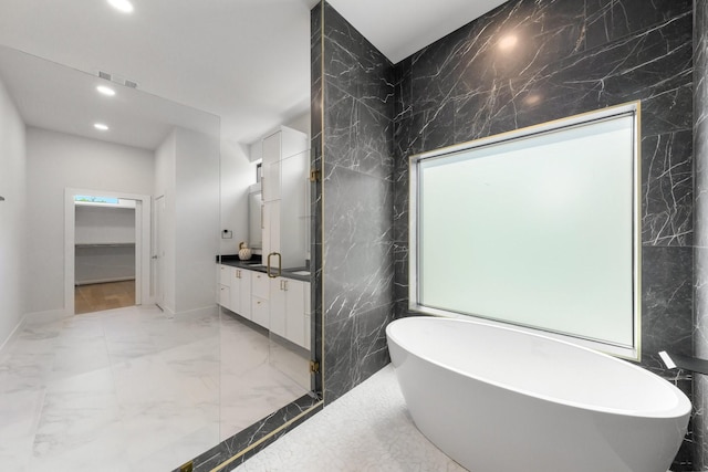 9409 Lenel Pl, Dallas, TX 75220 - full bath with marble tiled floors, recessed lighting, vanity, a soaking tub, and tile walls
