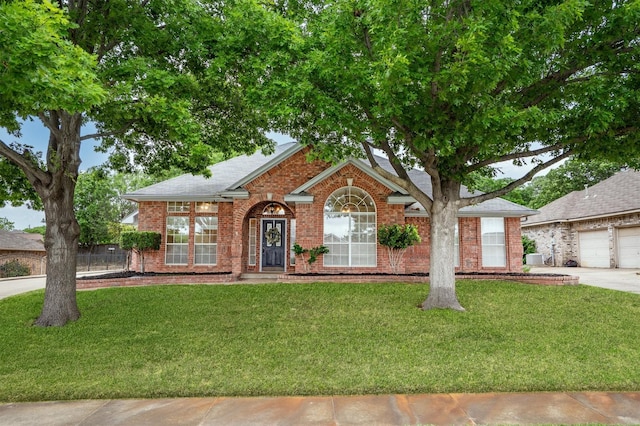 view of front facade featuring a shingled roof, concrete driveway, brick siding, and a front yard