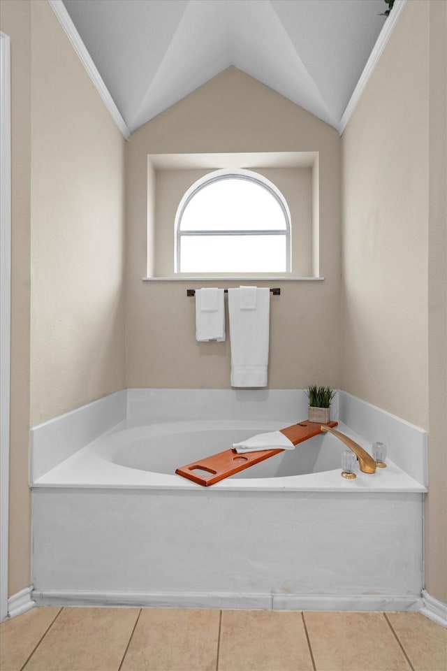 full bath with tile patterned floors, ornamental molding, lofted ceiling, and a garden tub