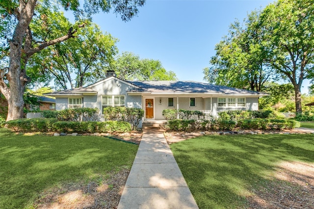 single story home featuring a chimney, brick siding, and a front yard