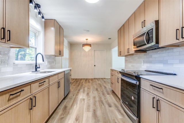 kitchen featuring backsplash, a sink, light brown cabinets, stainless steel appliances, and light wood-style flooring