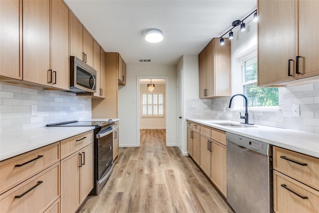 kitchen with visible vents, light brown cabinetry, a sink, light wood finished floors, and stainless steel appliances