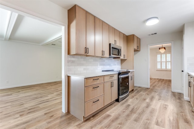 kitchen featuring tasteful backsplash, light countertops, baseboards, light wood finished floors, and stainless steel appliances