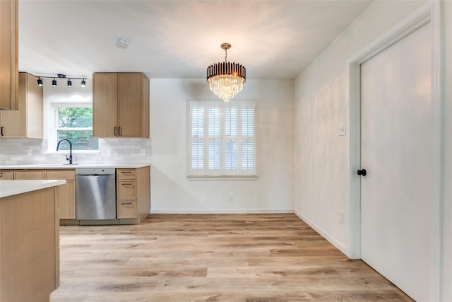 kitchen featuring backsplash, dishwasher, a sink, light countertops, and light wood finished floors