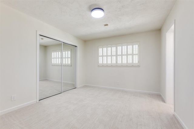 unfurnished bedroom with a closet, baseboards, carpet flooring, and a textured ceiling