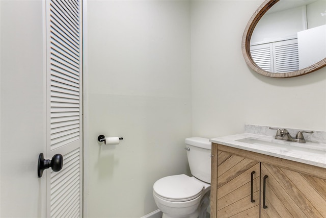 half bath featuring toilet, a closet, and vanity