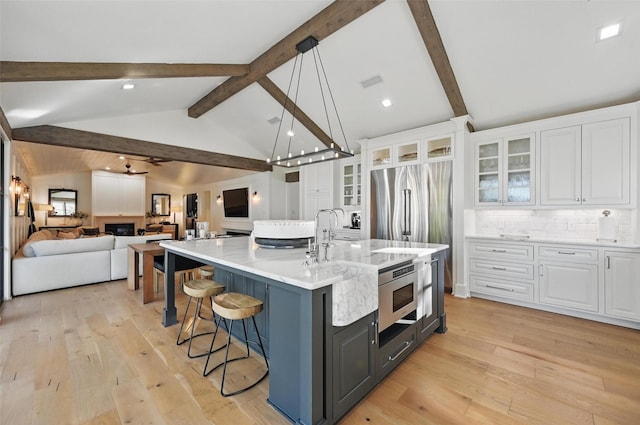 kitchen featuring lofted ceiling with beams, light wood-type flooring, and white cabinetry