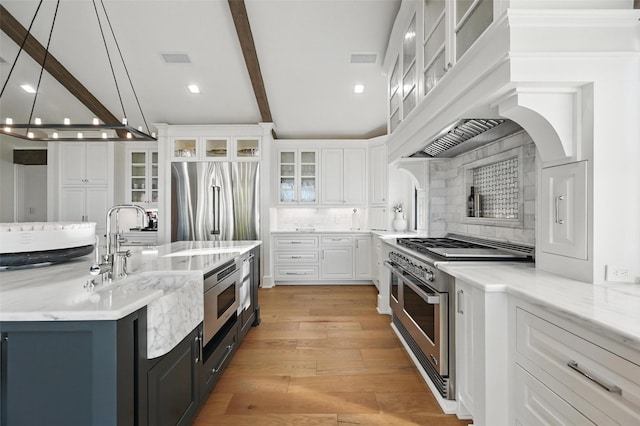 kitchen featuring high quality appliances, white cabinets, light wood-style flooring, backsplash, and exhaust hood