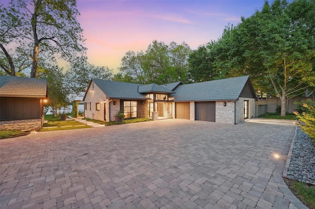 view of front of home featuring driveway, stone siding, and a garage