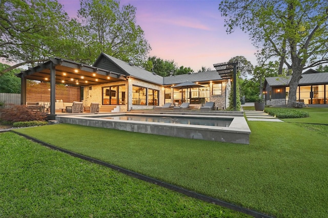 back of house at dusk with a patio, a yard, and an outdoor pool