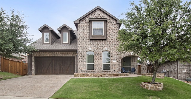 view of front of house with driveway, a front yard, a garage, brick siding, and fence