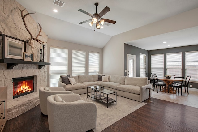 living room featuring a fireplace, a ceiling fan, wood finished floors, vaulted ceiling, and visible vents