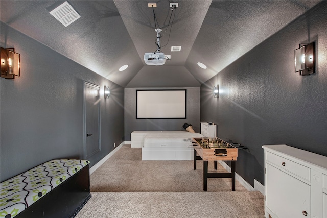 carpeted home theater with baseboards, a textured wall, lofted ceiling, and visible vents