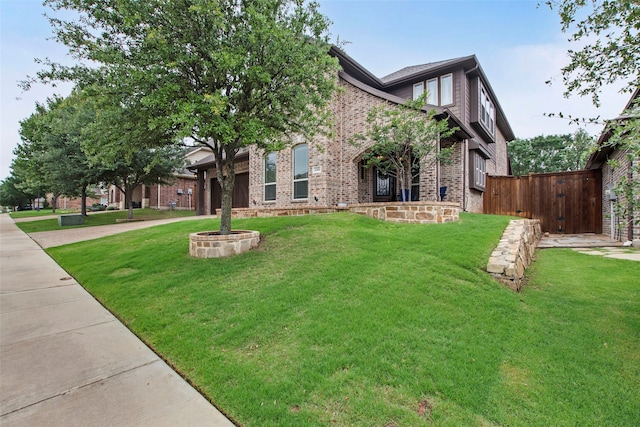 view of front facade with brick siding, a front lawn, an attached garage, and driveway