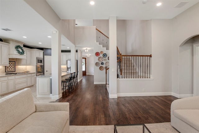 living room featuring stairs, visible vents, and wood finished floors