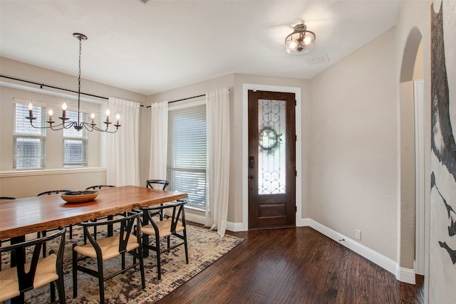entrance foyer featuring an inviting chandelier, arched walkways, baseboards, visible vents, and dark wood-style floors