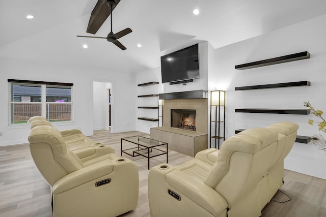 living room featuring wood finished floors, baseboards, ceiling fan, vaulted ceiling with beams, and a tiled fireplace