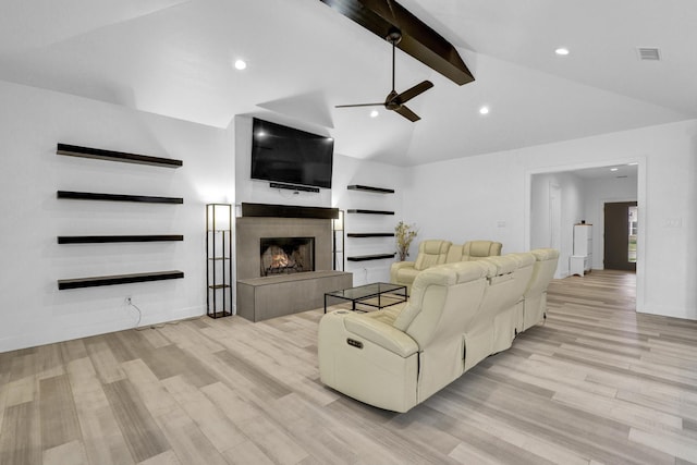 living room with a ceiling fan, visible vents, light wood-type flooring, a tile fireplace, and vaulted ceiling with beams