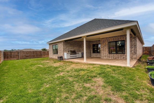 back of house featuring a fenced backyard, a patio, a lawn, and brick siding