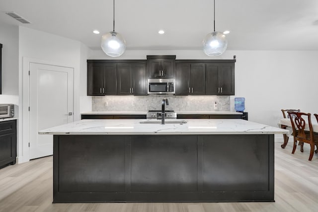 kitchen featuring light wood finished floors, stainless steel appliances, tasteful backsplash, visible vents, and pendant lighting