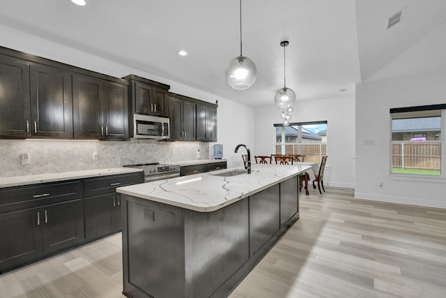 kitchen featuring visible vents, a sink, light wood-style flooring, backsplash, and stainless steel appliances