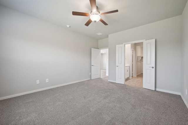 unfurnished bedroom featuring light colored carpet, a ceiling fan, baseboards, and connected bathroom