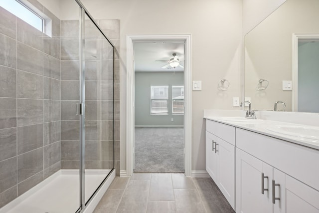 bathroom featuring double vanity, a ceiling fan, a shower stall, and a sink