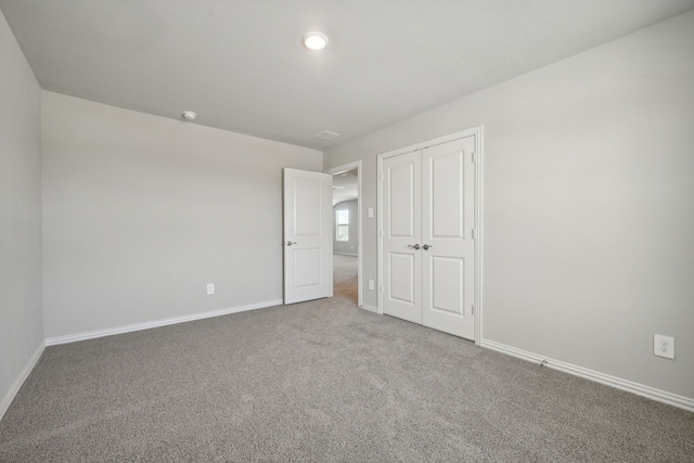 unfurnished bedroom featuring baseboards, carpet, and a closet
