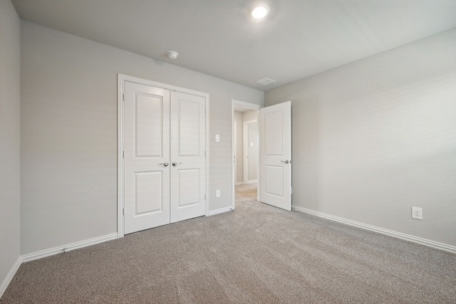 unfurnished bedroom featuring carpet floors, baseboards, and a closet