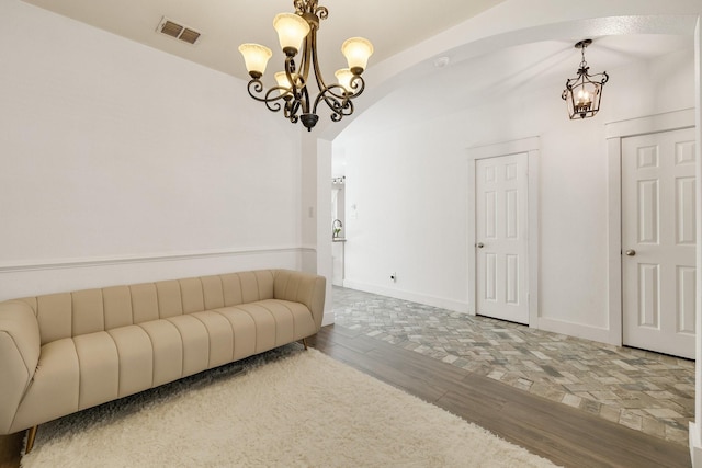 living room featuring visible vents, arched walkways, wood finished floors, baseboards, and an inviting chandelier