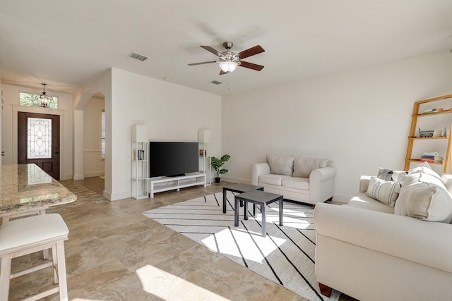 living area with visible vents, arched walkways, baseboards, and ceiling fan