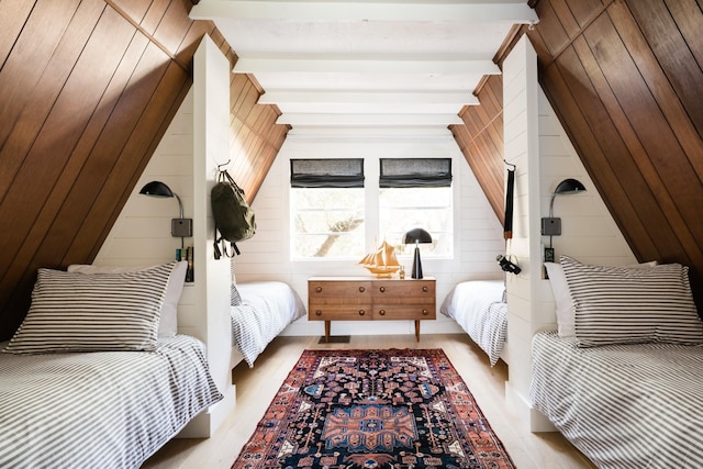 bedroom featuring beamed ceiling, wood walls, and wood finished floors