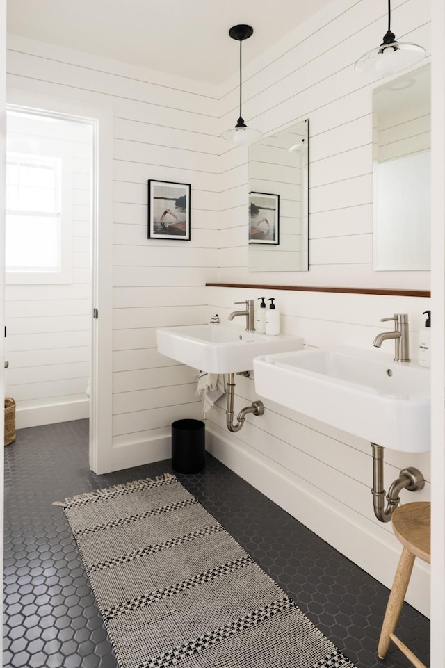 bathroom featuring a sink, tile patterned flooring, and wood walls