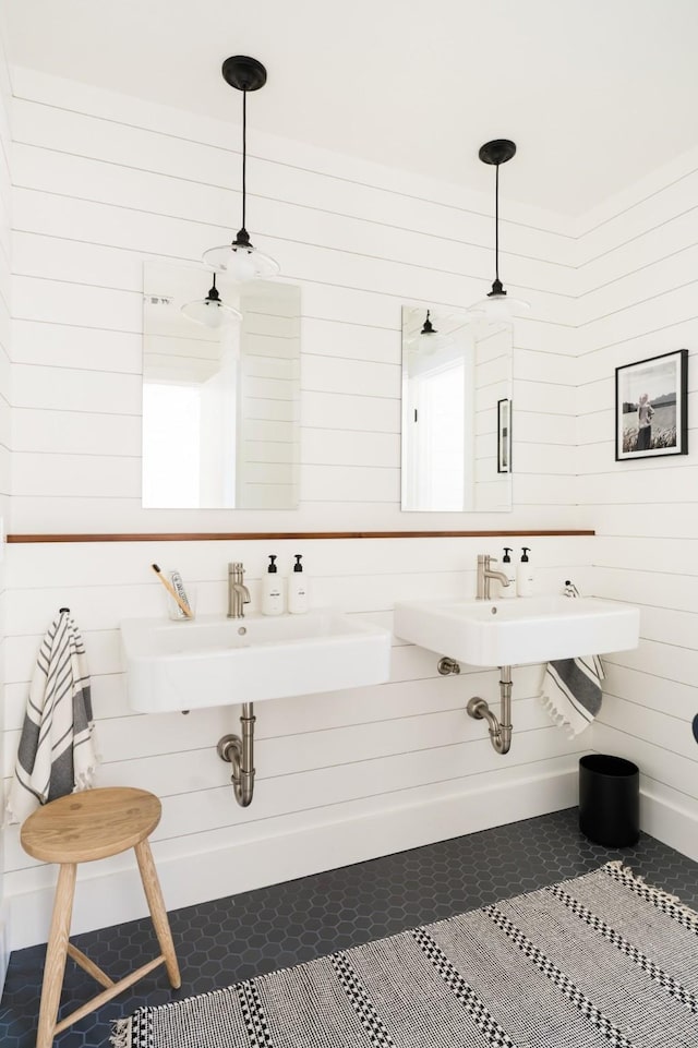 bathroom with tile patterned flooring, wood walls, and a sink