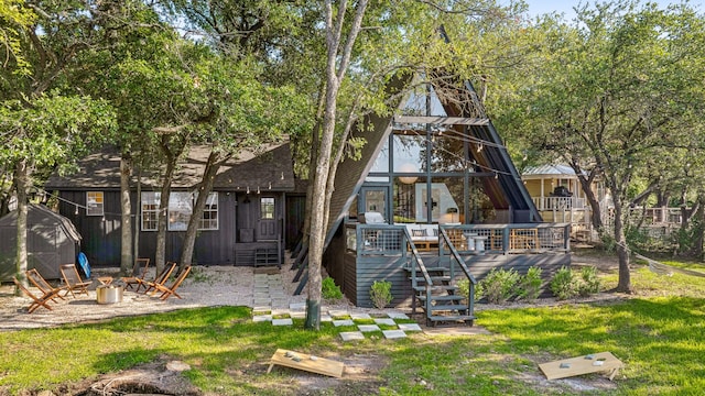 view of front of home featuring stairway, a wooden deck, a front yard, and an outdoor fire pit